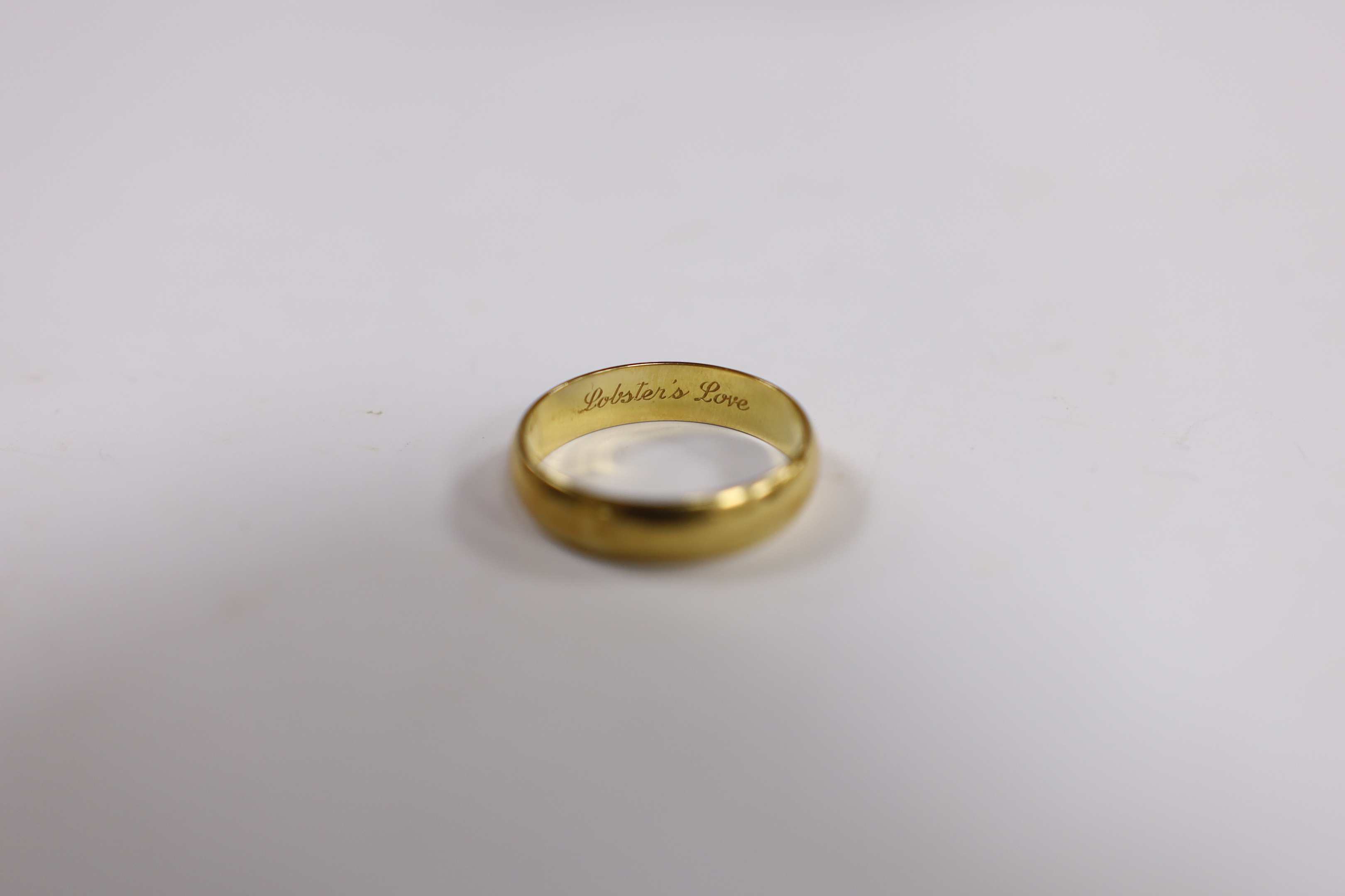 A modern Cartier 750 yellow metal wedding band, signed and numbered 62 JA 0005, with engraved inscription 'Lobster's Love', size U, 5 grams, with Cartier boxes.